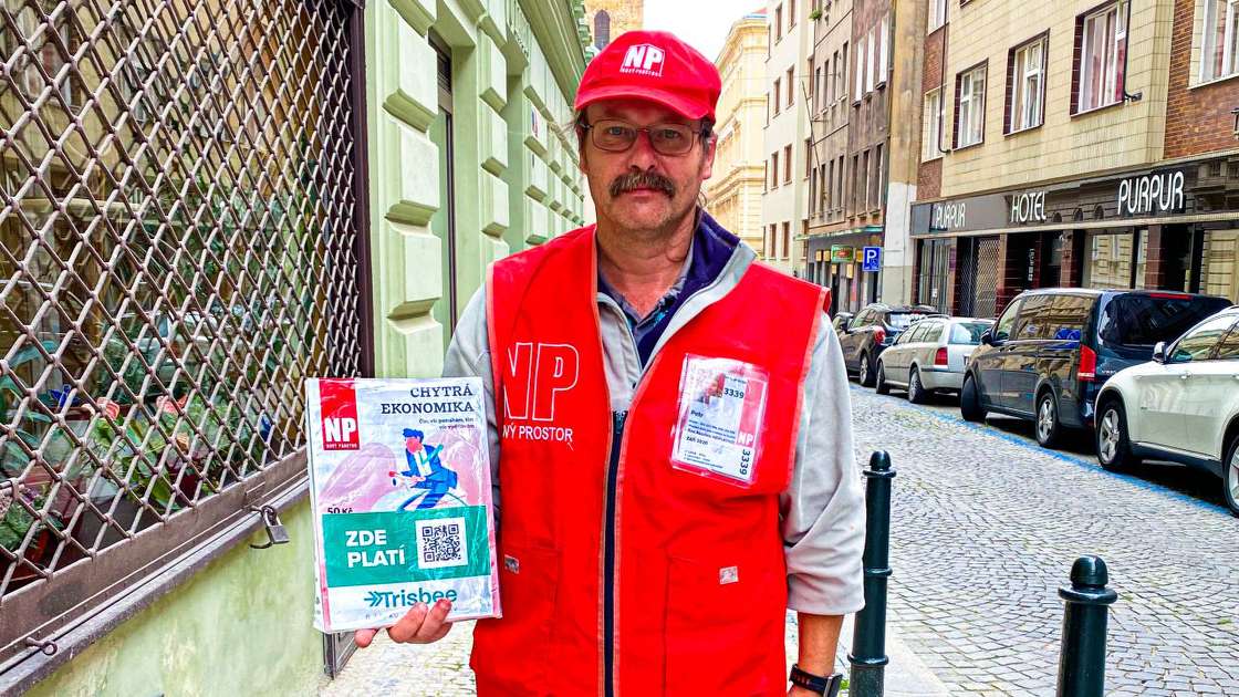 A Nový Prostor street vendor holding the magazine with a Trisbee QR code for paying